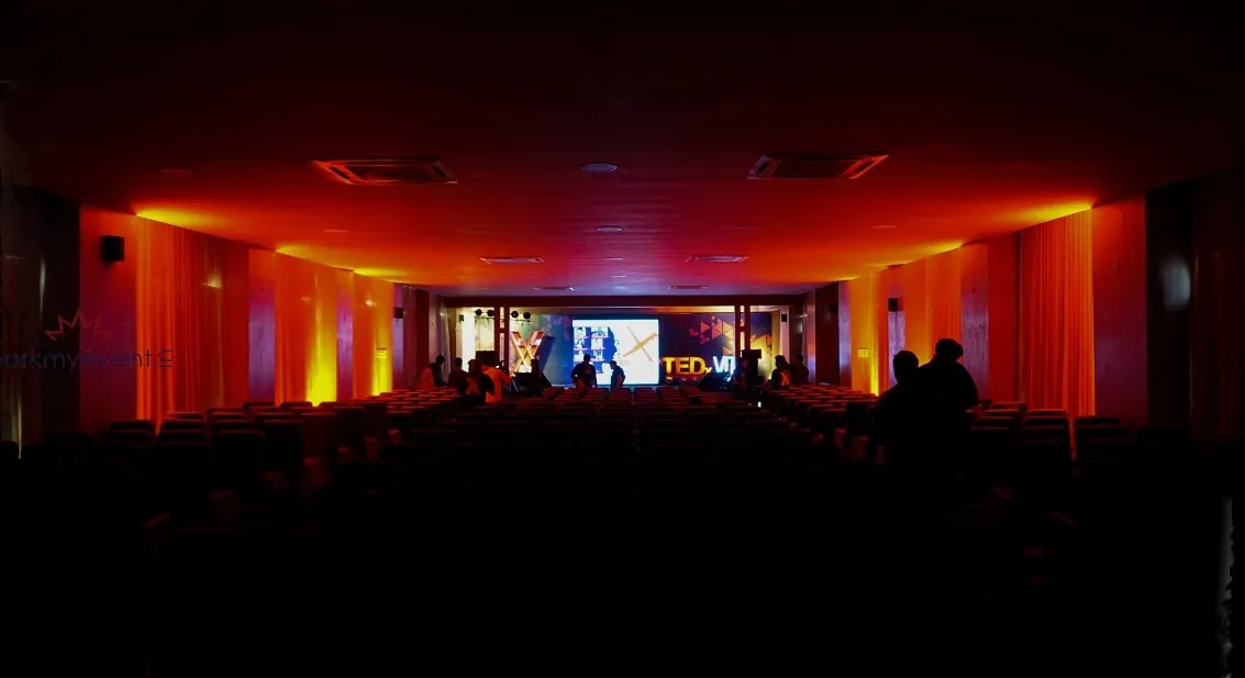 A hall lit in red and amber as the audience settles