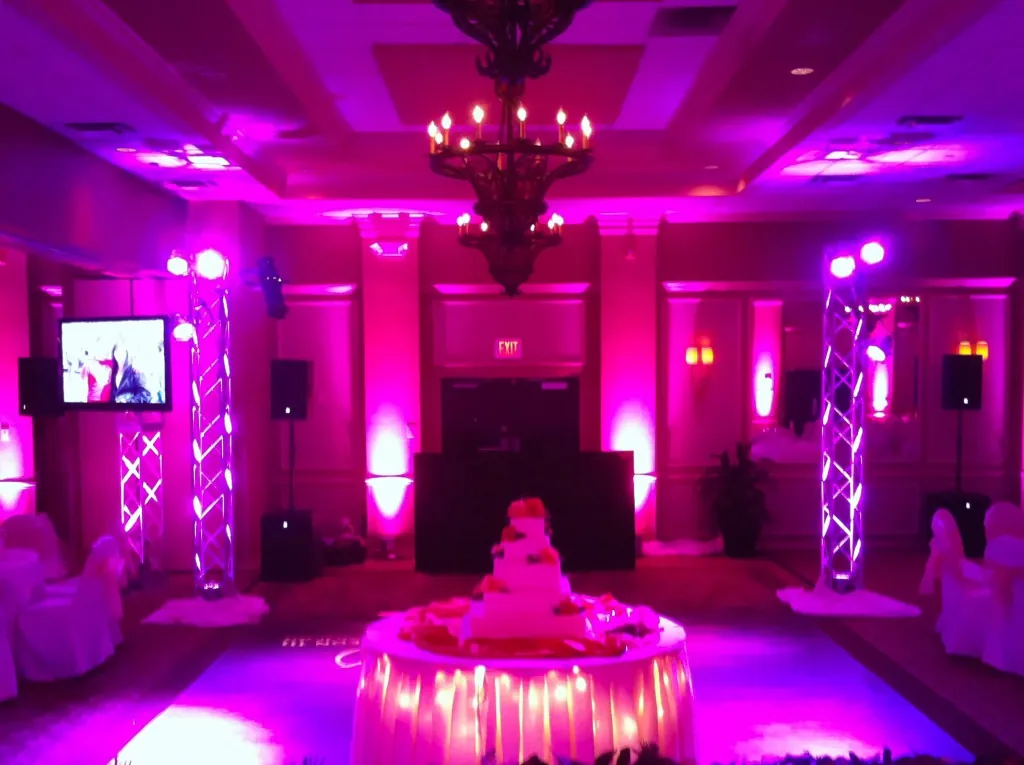 A ballroom washed in magenta light around a cake table