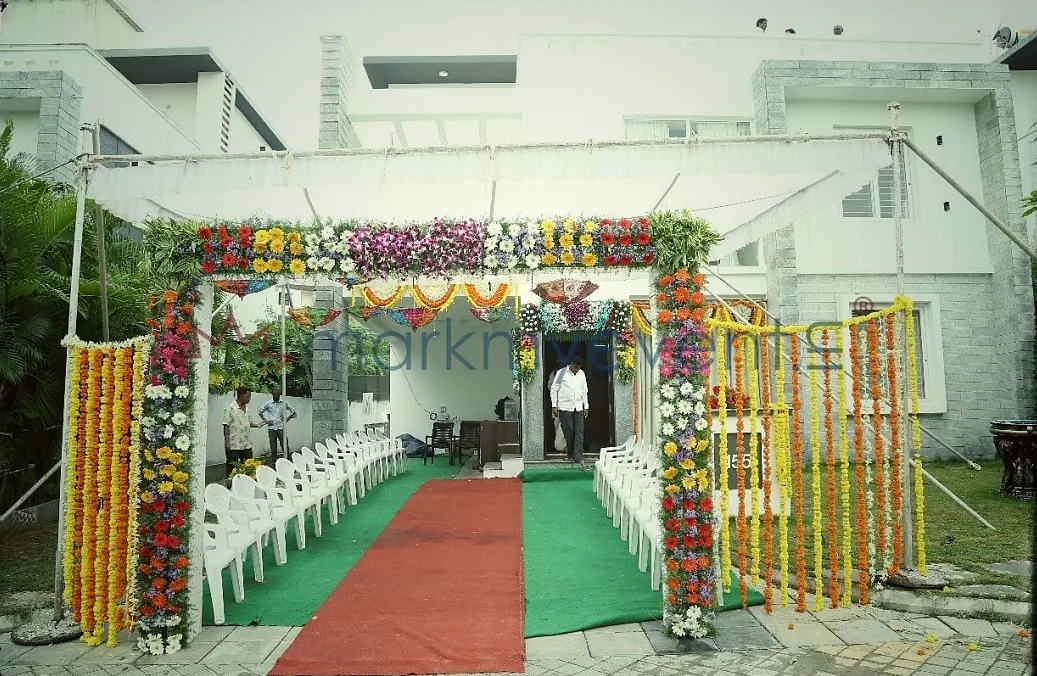 A flower-garlanded entrance with a red carpet leading in